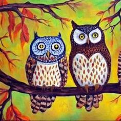 two owls sitting on a tree branch with leaves