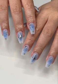 a woman's hands with blue and white nail designs on their nails, holding onto the tip of her fingers