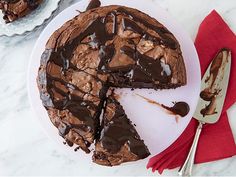 a chocolate cake on a white plate with one slice cut out and the other half eaten