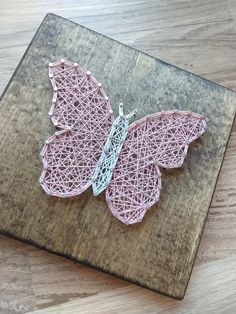 a string art butterfly sitting on top of a wooden board