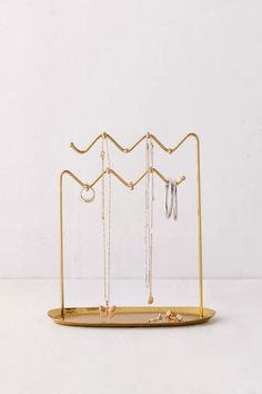 a gold jewelry holder with three necklaces and two earring hooks hanging from it