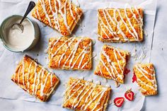 desserts with icing and strawberries laid out on a piece of parchment paper