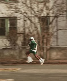 a man running down the street in front of a building with no leaves on it