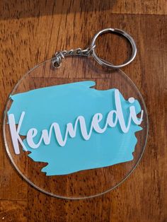 a glass keychain with the word kennedi painted in white on it