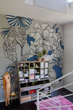 a room with flowers painted on the wall and a book shelf in front of it