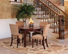 a dining room table with four chairs next to stairs