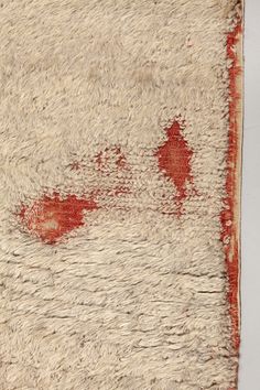 an old rug with red paint on it