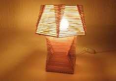 a lamp made out of books sitting on top of a white table next to a wall