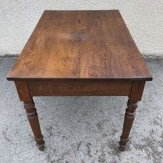 an old wooden table sitting in front of a white wall with no one on it