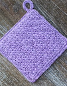 a purple crocheted pot holder on top of a wooden table