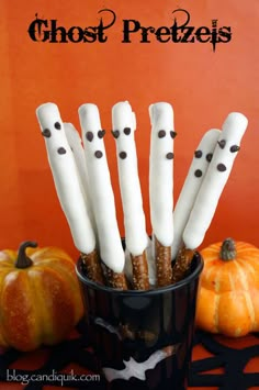 there are many white sticks with black dots on them in a cup next to pumpkins