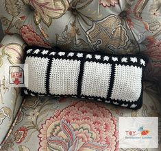 a black and white crocheted pillow sitting on top of a chair next to a cushion