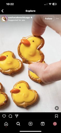 a person is holding some cookies with yellow icing on them and there are little rubber ducks in the middle