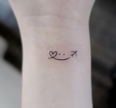 a smiley face tattoo on the wrist with an arrow in it's center and a heart at the bottom