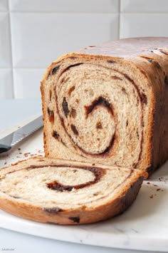 a loaf of cinnamon swirl bread sitting on top of a white plate next to a knife