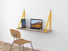 a laptop computer sitting on top of a wooden shelf next to a desk with a chair