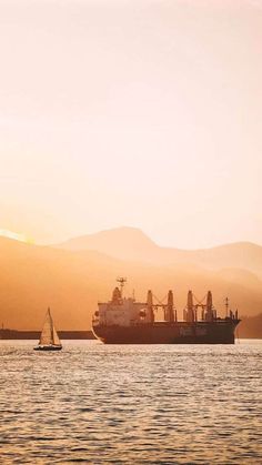 a large cargo ship sailing in the ocean at sunset