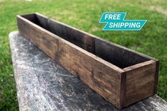 a wooden planter sitting on top of a cement bench in front of green grass