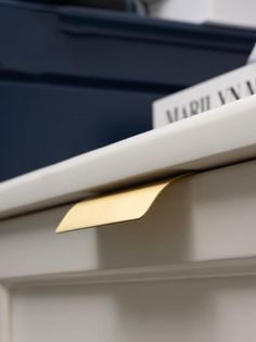 a close up of a metal object on top of a white shelf with a name plate