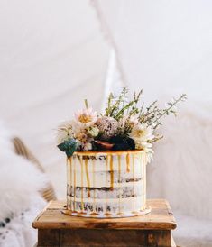 a cake sitting on top of a wooden table covered in frosting and fresh flowers