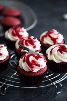 red velvet cupcakes with white frosting on a wire rack