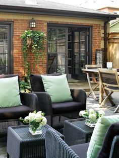 an outdoor patio with wicker furniture and green pillows