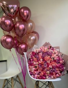 a bouquet of pink roses and balloons on a chair next to a vase with flowers