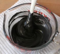 a glass bowl filled with black icing on top of a white towel