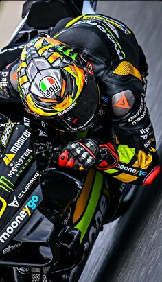 a man riding on the back of a motorcycle down a race track in a helmet