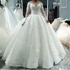 a woman is standing in front of dresses on display at a bridal shop wearing a wedding dress