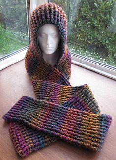 a knitted hood and scarf sitting on top of a wooden table next to a window