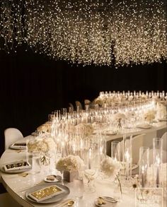 a long table is set with white flowers and candles for an elegant dinner or party