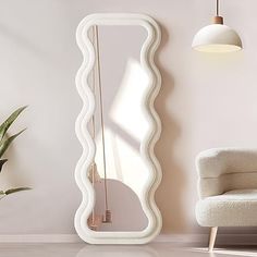 a white chair sitting next to a large mirror on the wall in a living room