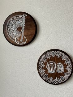 two wooden plates with designs on them hanging from the wall