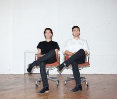 two men sitting on chairs in an empty room