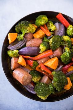 a bowl filled with vegetables and meat on top of a blue countertop next to a fork