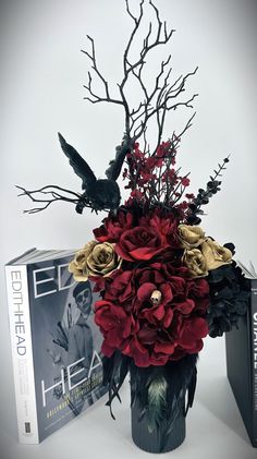 a vase filled with flowers next to a book on a white tablecloth and two black birds