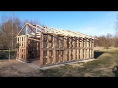 a house being built in the middle of a field with wood framing on it's sides