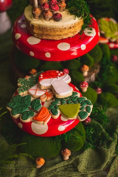 three tiered trays with cookies and other decorations on top of green leaves in the shape of mushrooms