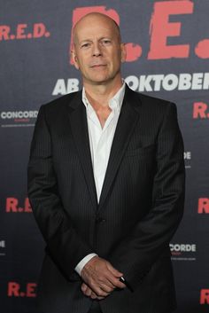 a bald man in a suit and white shirt posing for the camera at an event