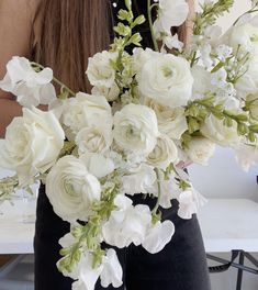 a woman holding a bouquet of white flowers