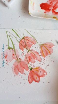 someone is painting flowers with watercolors on the paper and then using it to paint them