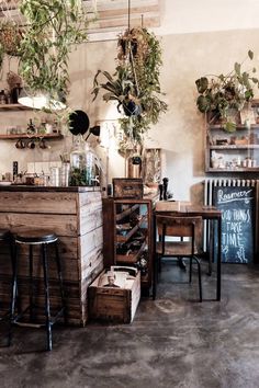 a room filled with lots of potted plants next to wooden tables and stools