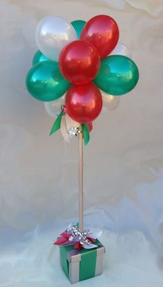 a bunch of balloons that are on top of a stick with a present in it