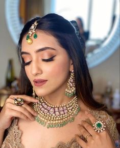 a woman in a gold and green outfit with jewelry on her neck, looking down at the