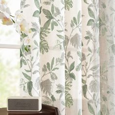 the curtains in this room are decorated with green and white floral designs, along with an alarm clock