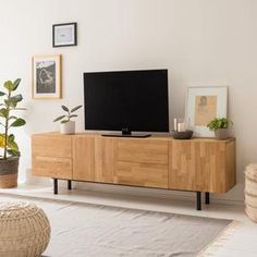 a flat screen tv sitting on top of a wooden entertainment center next to a potted plant