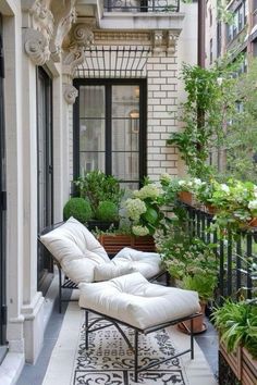 an outdoor patio with white furniture and potted plants on the balcony, surrounded by black iron railings