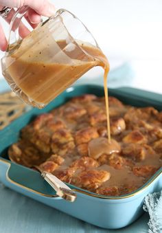 someone pouring caramel sauce on top of a casserole in a blue dish