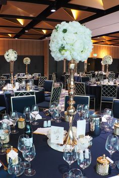 the tables are set up with blue linens and white flowers in tall vases